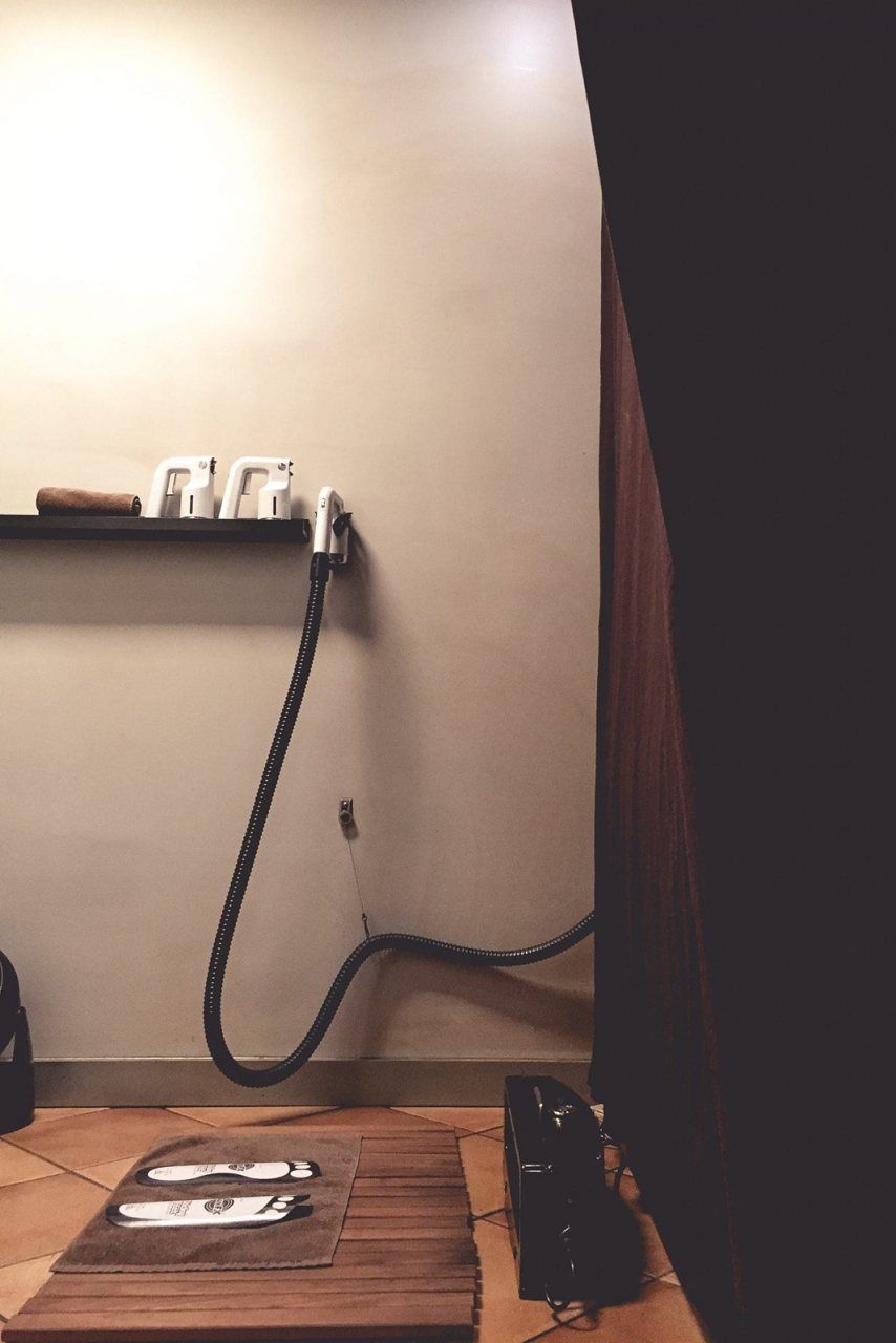 Warm lit room with dark curtains with spray tanning airbrush equipment and and protective clean surfaces.