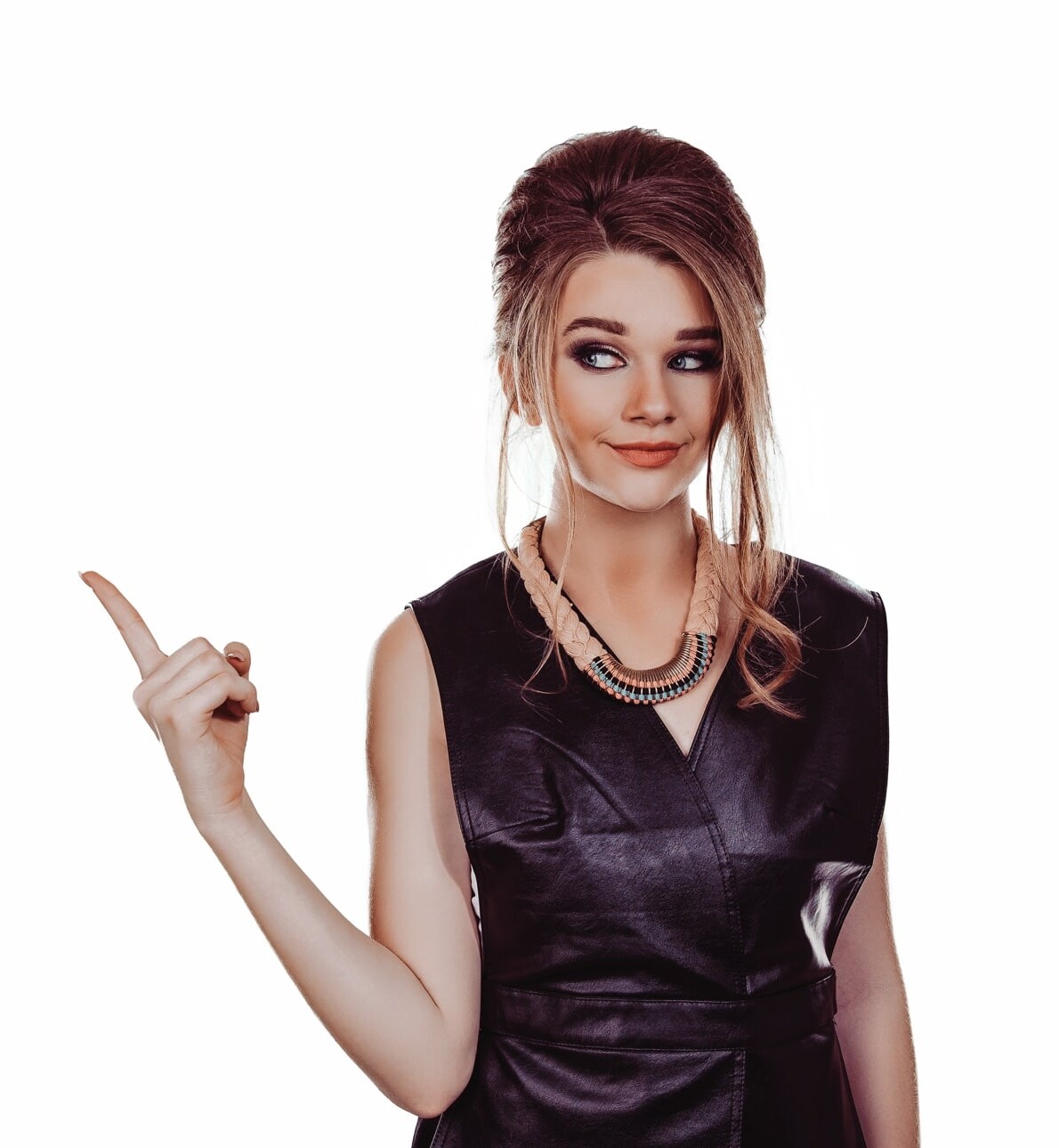 A woman with a beehive hairstyle and dark makeup is pointing to the left with her index finger. She is wearing a black sleeveless dress and a necklace, looking ready for her professional mobile spray tan session. The background is plain white.